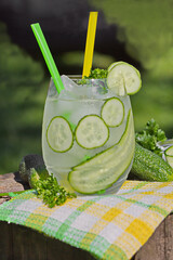 Detox cucumber diet drink. Healthy summer cooler on tree stump.  Cold fresh lemonade with cucumber and ice, selective focus.