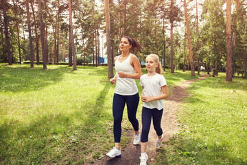 Fototapeta premium running sporty mother and daughter. woman and child jogging in a park. outdoor sports and fitness family.