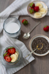 Healthy vegan chia seed pudding in a mason jar topped with strawberry and banana. Rustic and dark concept