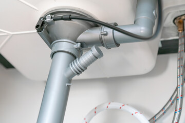 Grey plastic siphon pipes under the sink. Tubes for wastewater. Plumbing in kitchen. Repair. Water...