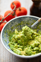 Mashed avocado in bowl. Chunky guacamole sauce