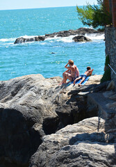 a family sitting on the rocks in the mediterranean sea