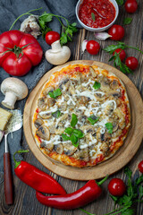 Homemade pizza with tomatoes, mushrooms and green basil.