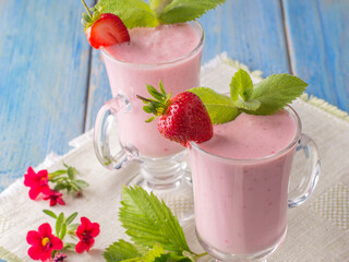 strawberry yogurt in a glass cup on a blue wooden table.
