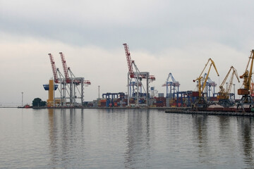 Obraz premium Containers in the port. Harbor cranes in cloudy weather.