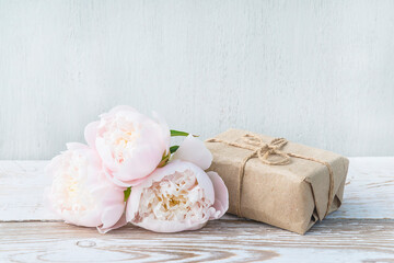 Romantic greeting card. Handmade gift box and white peonies on white paint wooden background. Space for text