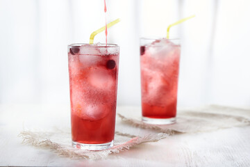Two glasses of ice cold lemonade with blackcurrant berries . Pour the syrup into the glass.