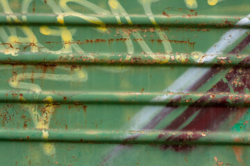 The surface of an old rusty carriage with graffiti elements