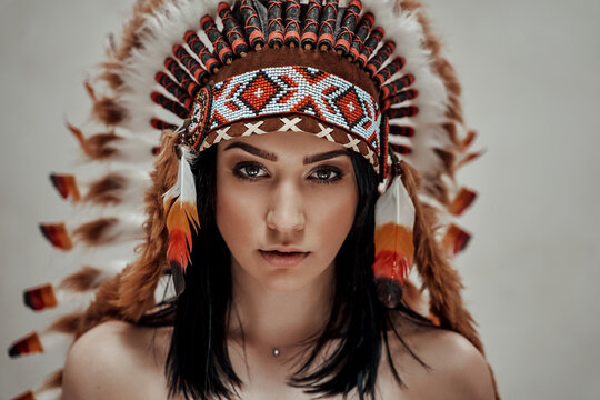 Close-up portrait of a nude female wearing feather mayan headdress, aztec conceptual look