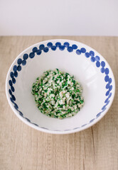 Porridge grains with spinach in a deep ethnic plate on a wooden background. Homemade food for lunch or dinner 