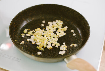 Fried onions cooked in a dark pan on a white induction cooker