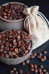 Coffee beans in an earthenware dish and a bag on a wooden table.