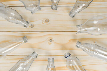 Empty glass bottles lined up in a round manner on light brown background. Top of glass bottles with copy and writing space.