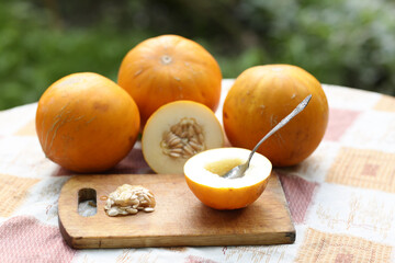 healthy food - whole and cut melon with seeds and teaspoon, kitchen board outdoor