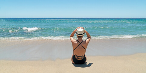 Fototapeta na wymiar luxury trip to Sardinia. Woman with a hat on the beach in villasimius 