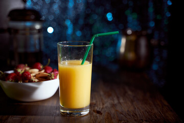 orange juice in a high glass with a green tube on a dark blue bokeh background. With copy space