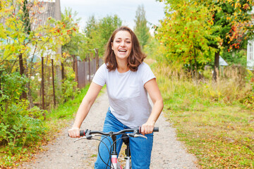 Fototapeta na wymiar Young woman riding bicycle in summer city park outdoors. Active people. Hipster girl relax and rider bike. Cycling to work at summer day. Bicycle and ecology lifestyle concept.