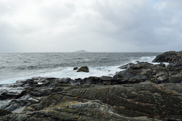 stormy windy day by the sea shore with majestic mountain in the distance on the island of Senja