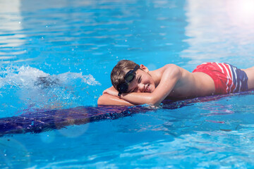 Kid boy playing in the swimming pool. Childhood, summer and vacation concept