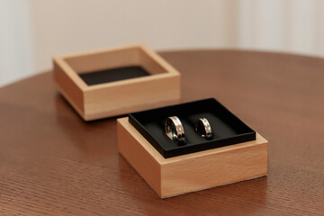 gold wedding rings lie in a wooden gift box on a glass black table