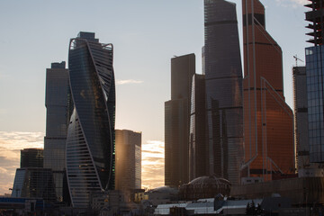 View of the high-rise buildings of the Moscow City complex through the Moscow river in the evening at sunset.

