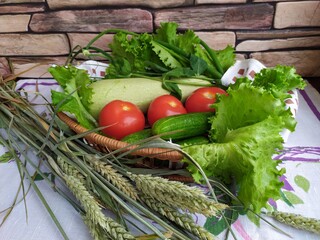 Still life in the kitchen vegetables zucchini cucumbers tomatoes onion salad fruit yellow pear on the table near the brick wall