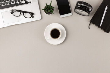 Flat lay of white espresso coffe cup with dish on light gray modern office desk with copy space