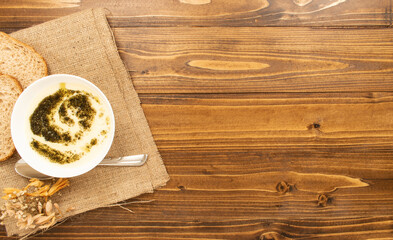 soup with yogurt on dark wooden background. making two slices of wheat next to it. lettering and copy space. top view.
