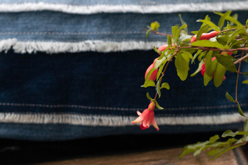 Upcycled old jeans canvas  and pomegranate flowers. Concept of things reuse and natural resources preserving. Selective focus.