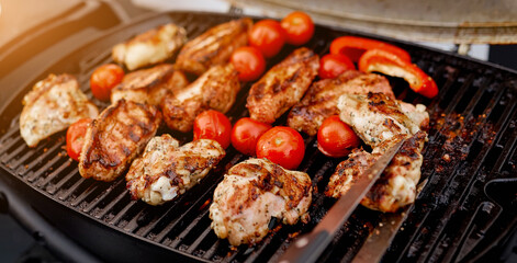 juicy roasted meat, tomatoes, red pepper on the grill on the street