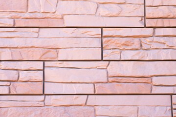 Fototapeta premium The texture of decorative stone for finishing the facade of a house with a light orange shade
