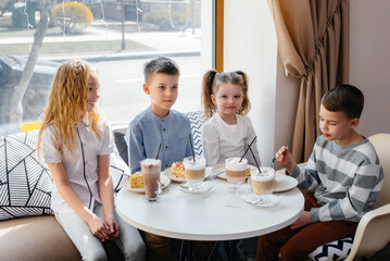 A large friendly company of children celebrate the holiday in a cafe with a delicious dessert. The day of the birth