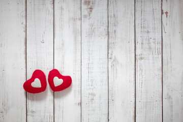 two red, textile, soft hearts on a light wooden background, place for text,