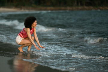 Mixed-race woman in the waves on the surf line on the sea beach.