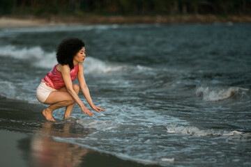 Mixed-race woman in the waves on the surf line on the sea beach.
