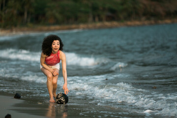 Woman of mixed-race in the waves on the surf line on the sea beach.