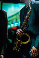 Jazz musician wearing suit playing saxophone in a dark neon night club.
