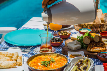 Concept promotional morning breakfast in the hotel, tasty Egg Benedict,Turkish and French Breakfast, tea and orange juice. near swimming pool in the garden