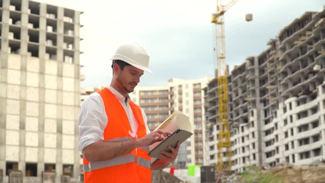 Architect or engineer working, browsing building project of construction site with tablet. Digital technologies in building construction