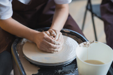 Female potter makes a pot on the pottery wheel close-up.
