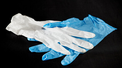 White and blue medical gloves on a black background