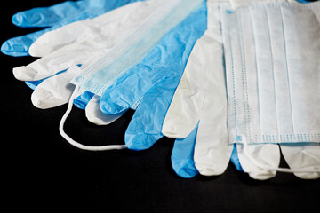 Blue and white medical gloves and medical masks on a black background