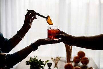 woman's hand and man's hand hold one glass with cocktail