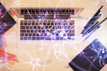 Neuron hologram drawings over computer on the desktop background. Top view. Multi exposure. Concept of education.