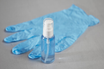 Tube with blue sanitizer and blue medical glove on a gray background