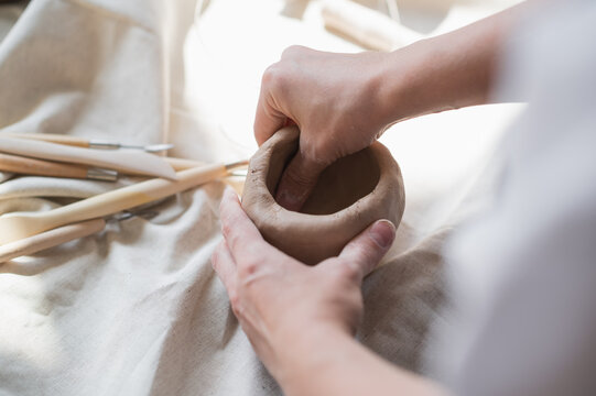 Professional female potter shaping and carving parts pottery workshop, studio. Crafting, artwork and handmade concept.