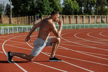 Obraz premium Shirtless athlete man making lunges at the stadium. Sportsman. Strong man