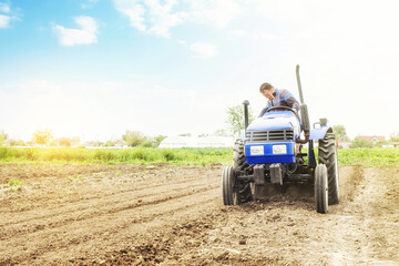 Farmer on a tractor with milling machine loosens, grinds and mixes soil. Loosening surface,...