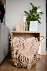 wicker basket with plaid inside standing on the floor in the room.