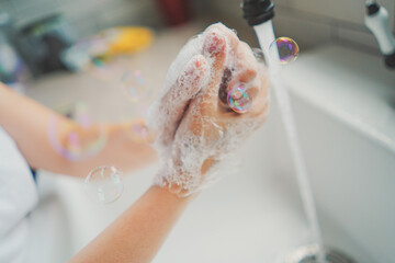 Fototapeta premium COVID-19 pandemic prevention wash hands with soap warm water and rubbing nails and fingers washing frequently, bubbles